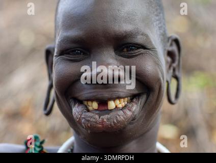 Donna sorridente della tribù surma con labbra e orecchie allargate, valle di Omo, Tulgit, Etiopia Foto Stock