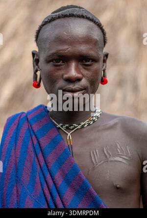 Uomo della tribù Surma con orecchio allargato e scarificazioni, valle dell'Omo, Tulgit, Etiopia Foto Stock