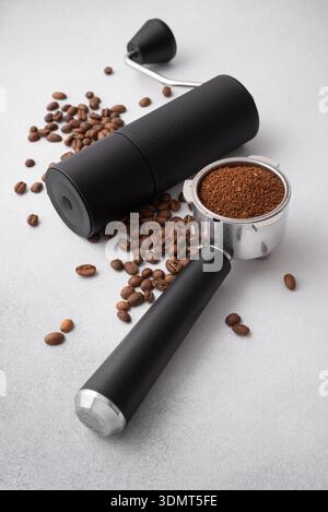 Macinacaffè manuale con chicchi tostati e portafiltro riempito con caffè macinato su uno sfondo chiaro. Concetto di caffè speciale, artigianalità, Foto Stock