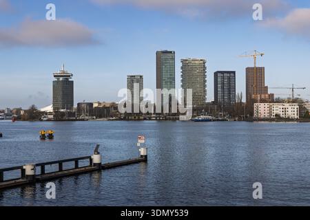 Moderno skyline del quartiere Nord di Amsterdam Overhoeks attraverso il fiume IJ con vista A'DAM e torri residenziali sotto un cielo mattutino blu. Foto Stock