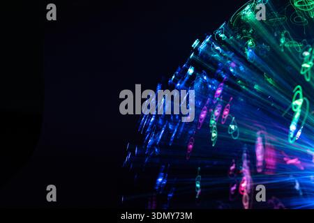Un'accattivante immagine astratta con lampade al neon che creano macchie vibranti in movimento dinamico. La miscela di colori su sfondo scuro evoca Foto Stock
