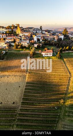 Una vista aerea cattura l'affascinante villaggio di Alice bel Colle all'alba, mettendo in evidenza gli intricati schemi dei vigneti e l'architettura storica Foto Stock