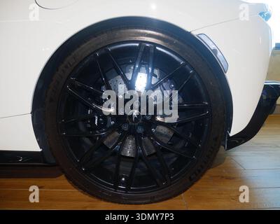 Primo piano di un cerchio ad alte prestazioni con cerchione in lega nera e pinze dei freni visibili, su uno sfondo in legno Foto Stock