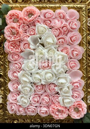 Fiori finti rosa e bianchi in una cornice color oro. Foto Stock