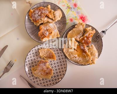 Vista dall'alto delle fette di torta di mele fatte in casa servite su tre piatti bianchi con forchette, dessert fresco e delizioso dall'alto, composizione piatta. Foto Stock