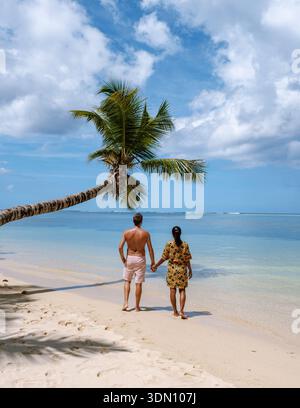 Una coppia romantica passeggia lungo le tranquille rive della spiaggia di Anse Royale nelle Seychelles, godendosi il caldo sole e la dolce brezza dell'oceano. Foto Stock