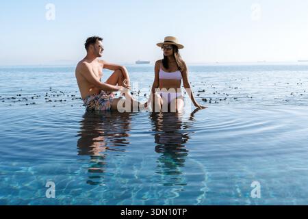 Nelle tranquille acque di città del Capo, una coppia condivide un momento di gioia, seduti in onde poco profonde mentre la luce del sole proietta un caldo bagliore. un uomo e una donna ad an Foto Stock