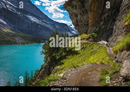 Bellissimo sentiero escursionistico con vista mozzafiato sulla riva del lago Oeschinensee sotto alte scogliere, Kandersteg, Oberland Bernese, Svizzera, Europa Foto Stock
