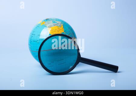 Globo e lente d'ingrandimento che rappresentano temi di esplorazione, ricerca e scoperta globali Foto Stock