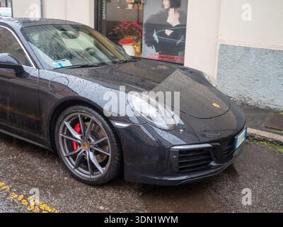 Cremona, Italia 6 febbraio 2026 Porsche 911 Carrera - serie 991 - auto sportiva bagnata dalla pioggia, con vernice grigio scuro, pinze dei freni rosse e lega Foto Stock