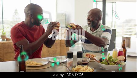Tostare padre-figlio indossando polo a righe, tee rosso con hamburger al bancone della casa, patatine fritte e icone AR Foto Stock