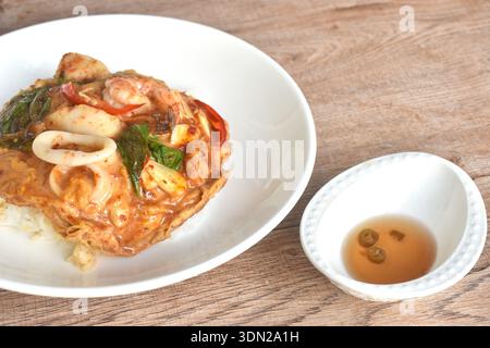 Curry rosso tailandese al vapore con frutti di mare su frittata all'uovo di panna e riso in piatto Foto Stock