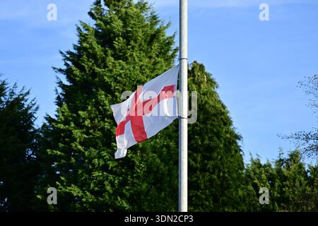 Bandiera dell'Inghilterra a mezz'asta su sfondo blu Foto Stock
