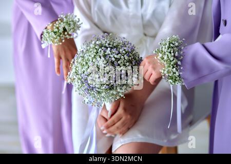 Sposa e damigelle che tengono mazzi di gypsophila e corsaggi floreali da polso Foto Stock