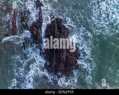 Vista aerea delle onde che si infrangono sulla costa rocciosa Foto Stock