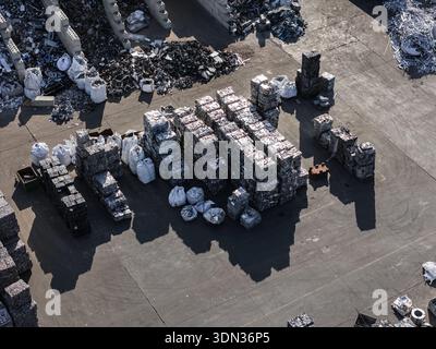 Vista aerea di un impianto di riciclaggio dei metalli riempito di pile di rottami metallici trasformati e di materiali di scarto destinati al riciclaggio e al riutilizzo. Foto Stock