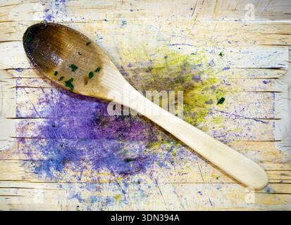 consistenza ulinaria, un cucchiaio di legno con frammenti di verdure sopra un tagliere con macchie di verdura e cavolo rosso Foto Stock
