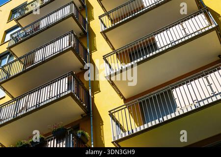 Moderno edificio di appartamenti di colore giallo con balconi e ombre geometriche Foto Stock