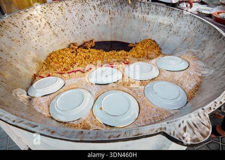 Cucina di plov nel grande piatto Kazan a Plov Centro di Tashkent, Uzbekistan Foto Stock