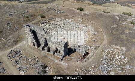 Vista dall'alto verso il basso con drone che mostra la disposizione semicircolare del teatro romano ad Acinipo e i resti archeologici circostanti. Foto Stock