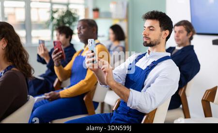 Il lavoratore scatta una foto con il telefono cellulare o fotografa il codice QR sulla bacheca in classe Foto Stock