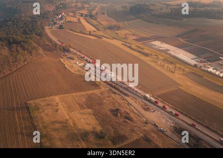 Camion dei vigili del fuoco su una strada di campagna con vista sui campi circostanti e sul villaggio al crepuscolo, esercitazione antincendio sulla ferrovia Hermann Hesse, Ostelsheim, Germania Foto Stock