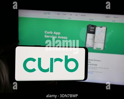 Stoccarda, Germania - 02-02-2026: Persona che possiede uno smartphone con il logo della società statunitense di applicazioni taxi Curb Mobility LLC sullo schermo di fronte al sito web. Foto Stock