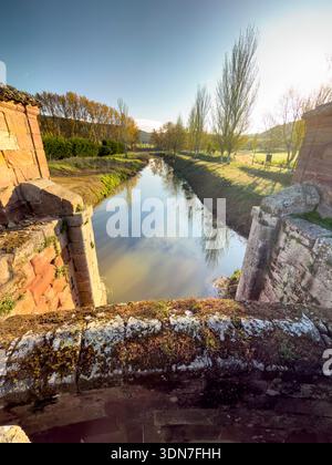 Antico sistema di chiuse del Canal de Castilla nell'Alar del Rey che si riflette sulle acque calme Foto Stock