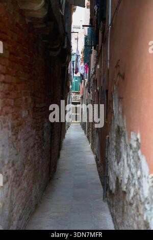 Vicolo stretto e scuro a Venezia con vecchie pareti in mattoni Foto Stock
