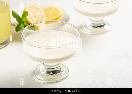 Dessert cremoso al limone con limoncello servito in un'elegante ciotola di vetro su sfondo chiaro, dessert fresco agli agrumi. Foto Stock