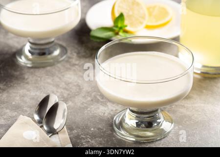 Classico dessert al limone con limoncello servito in una ciotola di vetro su un tavolo di pietra, elegante fotografia di dessert placcata. Foto Stock