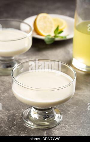 Classico dessert al limone con limoncello servito in una ciotola di vetro su un tavolo di pietra, elegante fotografia di dessert placcata. Foto Stock