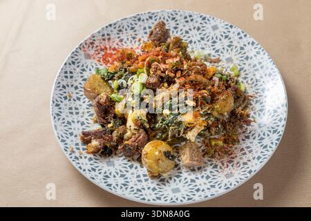 Piatto tradizionale greco di tenera carne di capra brasata servito con verdure selvatiche saltate (horta), condito con erbe aromatiche e un pizzico di spezie, presente Foto Stock