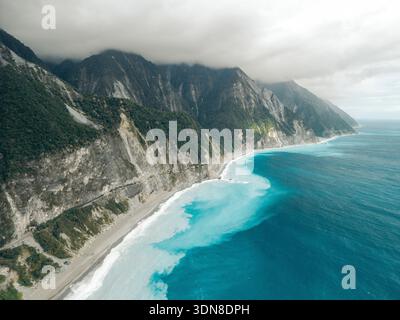 Le spettacolari scogliere costiere incontrano il luminoso oceano blu sotto un cielo nuvoloso. Costa della contea di Hualien, Xiulin Township, Taiwan Foto Stock