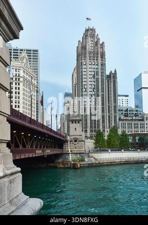 Vista di un ponte su un fiume turchese con uno storico grattacielo sullo sfondo. Chicago, Illinois, Stati Uniti Foto Stock