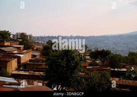 Vista del paesaggio urbano con alberi e tetti sotto un cielo nebuloso in una città collinare. Kigali, Ruanda Foto Stock