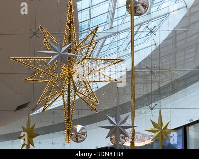 Stella dorata dal design sofisticato, luminosa e luminosa, si abbina a scintillanti stelle d'argento e d'oro, adornando un elegante e moderno spazio pubblico con tetto in vetro, aggiungendo fes Foto Stock