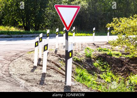 Segnaletica stradale "Give Way" quando si esce da una strada secondaria per la strada principale. Lascia spazio al traffico sulla strada principale. Esci dalla strada secondaria verso la strada principale Foto Stock