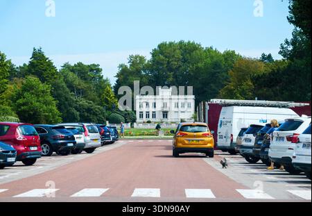 Le Touquet, Francia - 22 agosto 2023: Incrocio Zebra che conduce al parcheggio con veicoli colorati, auto gialla, furgoni bianchi ed elegante villa bianca Foto Stock