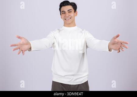 Uomo sorridente che apre le braccia per un abbraccio in studio Foto Stock