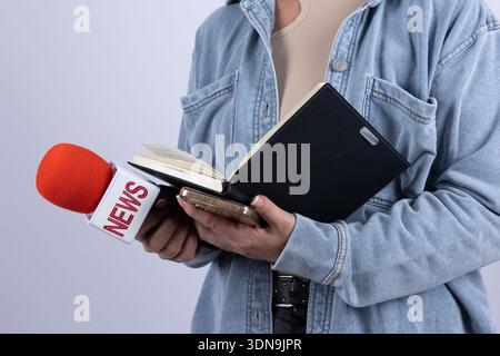 Reporter con un microfono rosso e un notebook Foto Stock
