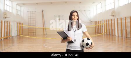 Allenatore di calcio femminile che posa all'interno di una palestra scolastica Foto Stock