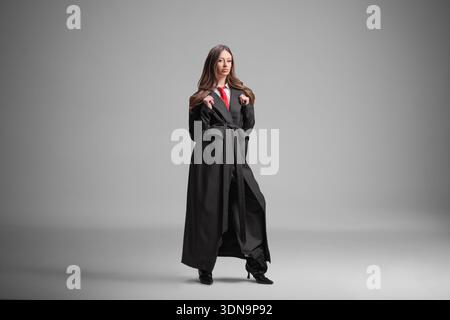 Donna elegante con un lungo cappotto nero e una cravatta rossa Foto Stock