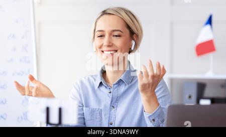 Una donna si impegna a conversare online mentre utilizza gli auricolari in ufficio nel pomeriggio Foto Stock