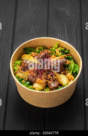 Insalata di fegato calda con pere caramellate, verdure miste e cipolle croccanti in kraft Bowl Foto Stock