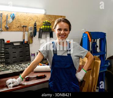 Ritratto di una meccanica sorridente nell'officina di riparazione auto. Foto Stock