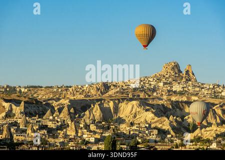 Turchia, Anatolia centrale, provincia di Nevsehir, Cappadocia, Göreme, camini delle fate, mongolfiere che decollano all'alba con Uchisar sullo sfondo Foto Stock