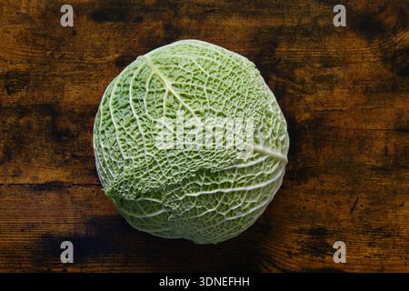 Un chou vert posé sur une planche en bois / Un cavolo verde su una tavola di legno Foto Stock
