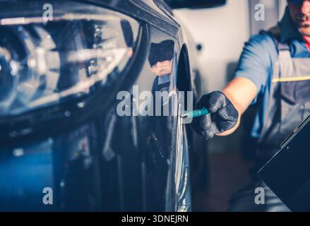 Un tecnico lavora su un'auto in un'officina, controllando lo pneumatico o la ruota. Foto Stock