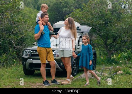 Una famiglia felice che si diverte con un'indimenticabile avventura all'aria aperta insieme nel loro SUV circondato da Natures Beauty Foto Stock